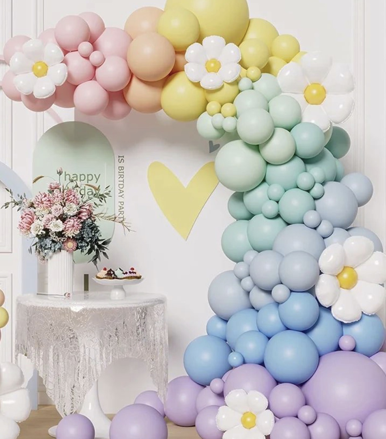 Pastel balloon arch with flowers and dessert table