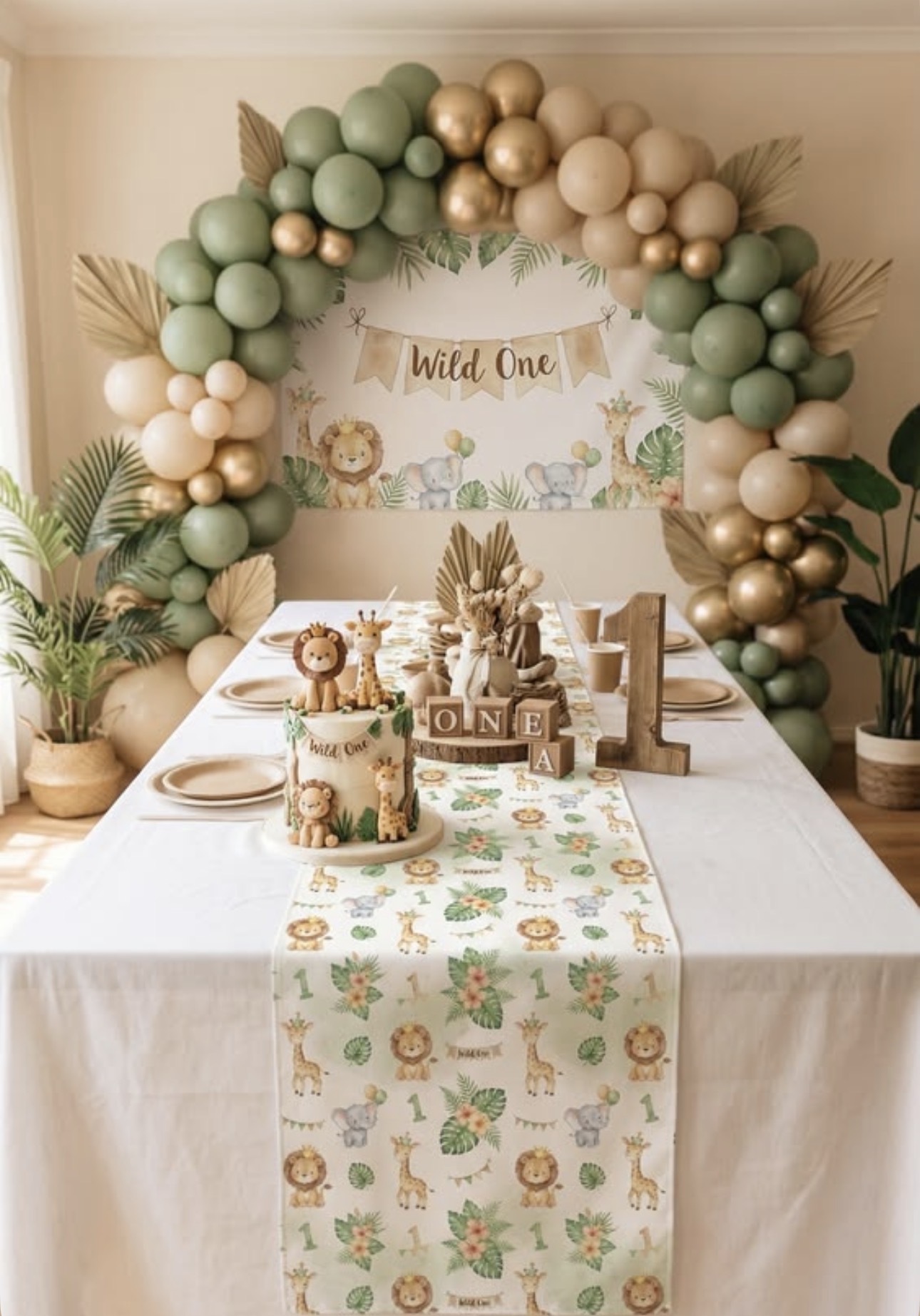 Jungle first birthday table with green balloon arch
